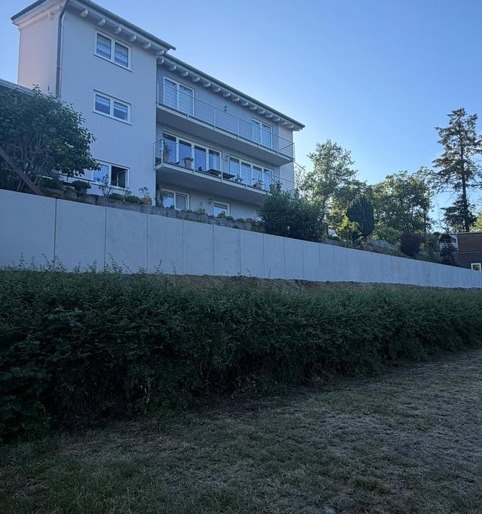 Grünfläche mit Hecke an der Stützmauer