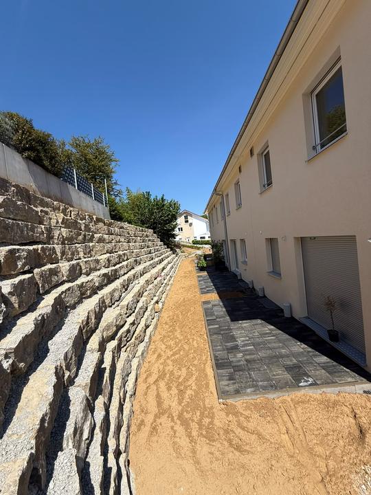 Natursteinmauer am Hang mit Pflasterweg